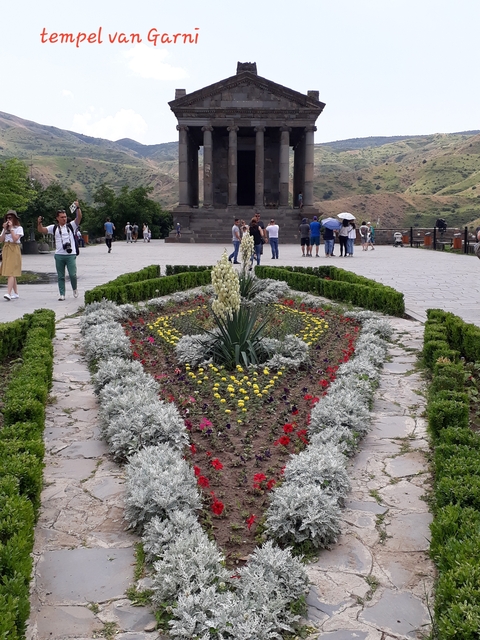 Landscaped garden in front of a historic building with tourists.