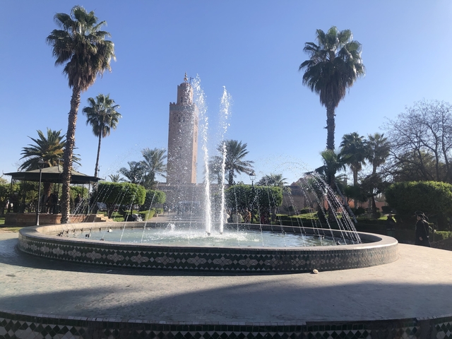 Fountain in a park with a towering minaret.