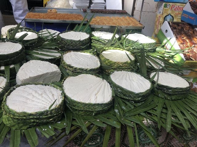 Rows of cheese wrapped in leaves on display.