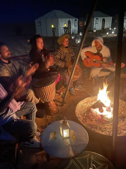 Group of people enjoying a night around a campfire with music.