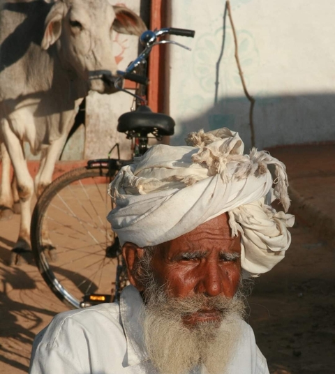 Portrait of a local man in traditional attire with a bicycle in the background.