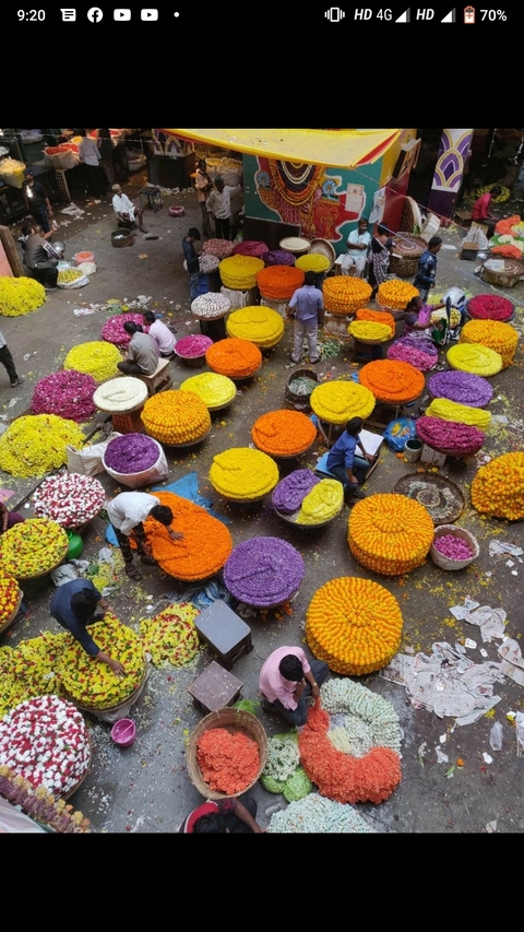 Vibrant market scene with baskets of colorful flowers and people.