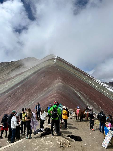 Group of people hiking along a colorful hillside with Andean scenery.