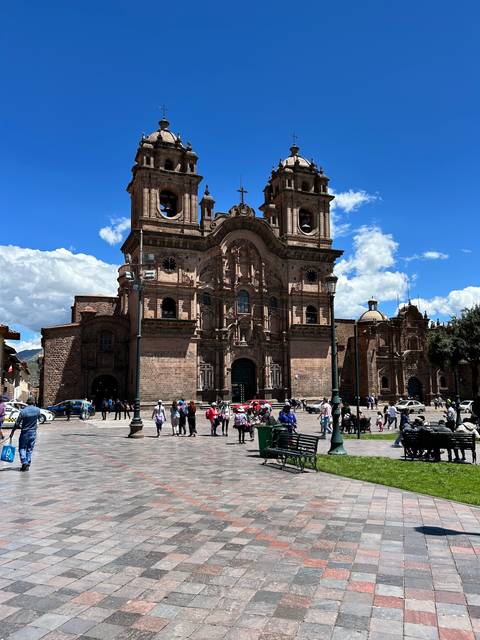 Historic cathedral in a busy square with tourists walking around.