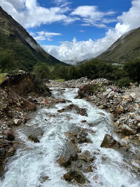 Rushing river flowing through a rocky landscape with mountains.