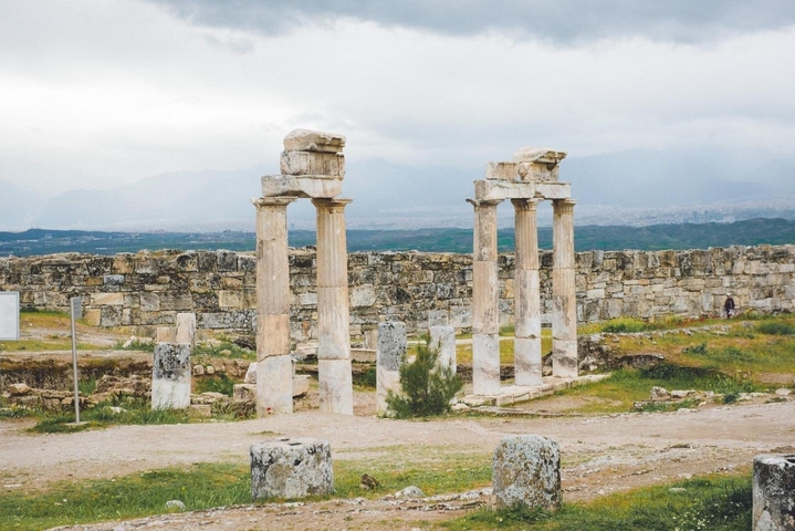 Three standing Roman columns of Hierapolis ruins under a grey sky