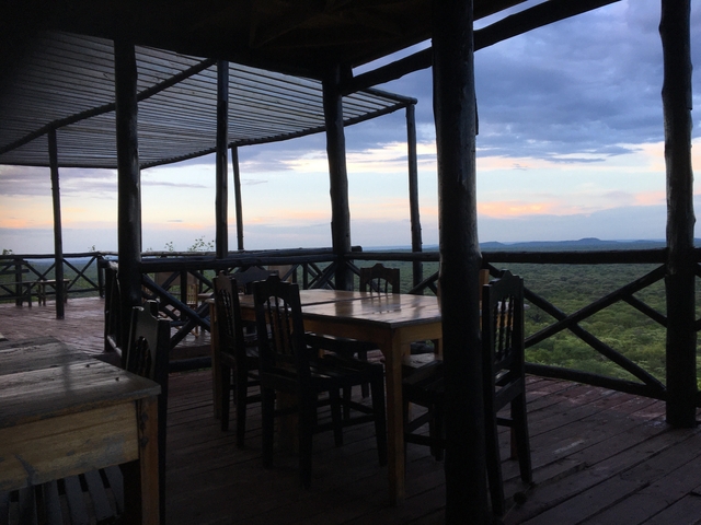 Outdoor wooden deck with tables and chairs overlooking a forest