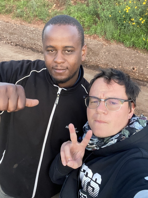 Casual selfie of guide and traveler flashing peace sign on a dusty road