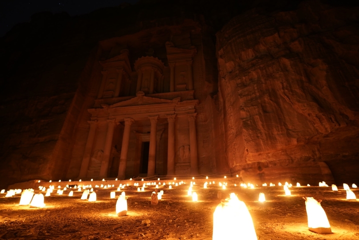 Hundreds of candles illuminate Petra’s Treasury façade, casting warm light against the sandstone walls at night.