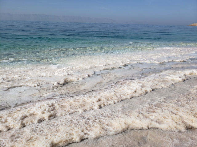 Crystalline salt formations line the shore where turquoise waters meet the Dead Sea’s pale shoreline.