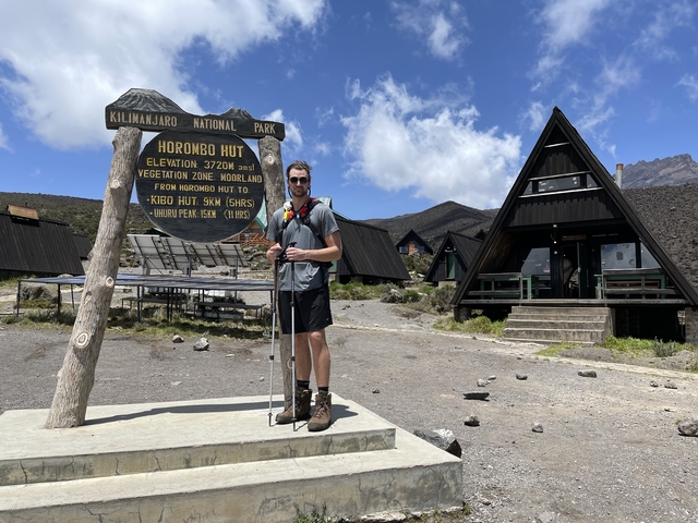 Hiker standing next to the Horombo Hut sign.