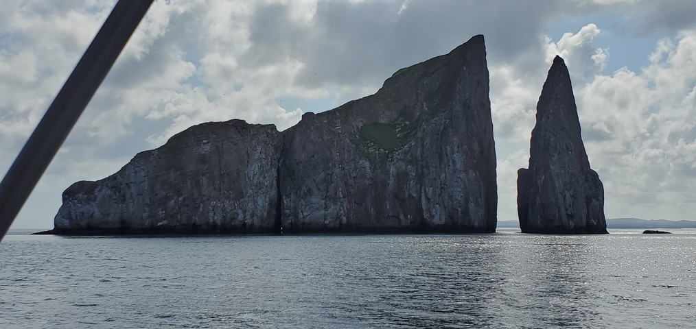 Dramatic rock formations by the sea under cloudy skies.