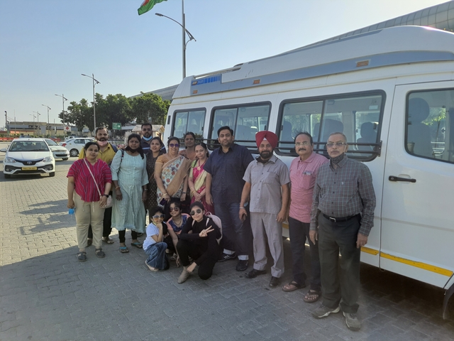 Group of people posing in front of a white bus in a parking area.