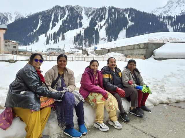 Group of women seated in the snow with a mountain backdrop.