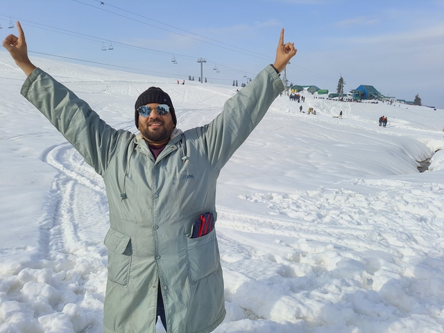 Person raising arms joyfully in a snowy landscape.