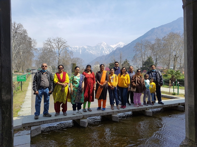 Group of people posing in a park with mountains in the background.