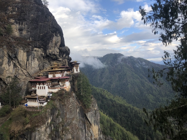 Iconic Tiger’s Nest Monastery clings dramatically to a sheer cliff amid Bhutan’s lush green mountains and clouds.