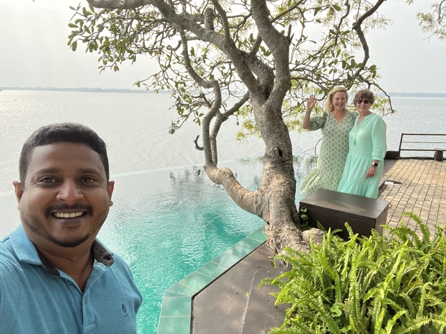 People standing by an infinity pool at a lakeside resort.