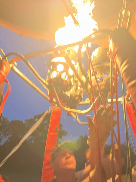 Hot air balloon burner in close-up with flame and person.