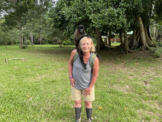 Woman smiling with a monkey on her shoulder.