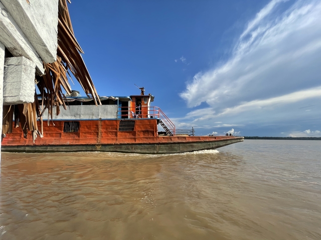 Boat moving in a river under a blue sky.