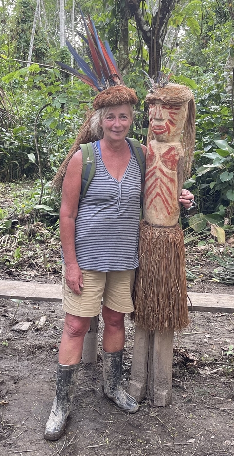 Close-up of a person standing next to a wooden statue.