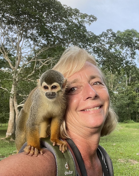 Close-up of a woman smiling with a small monkey.