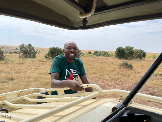 Person smiling in a safari vehicle in the savannah.