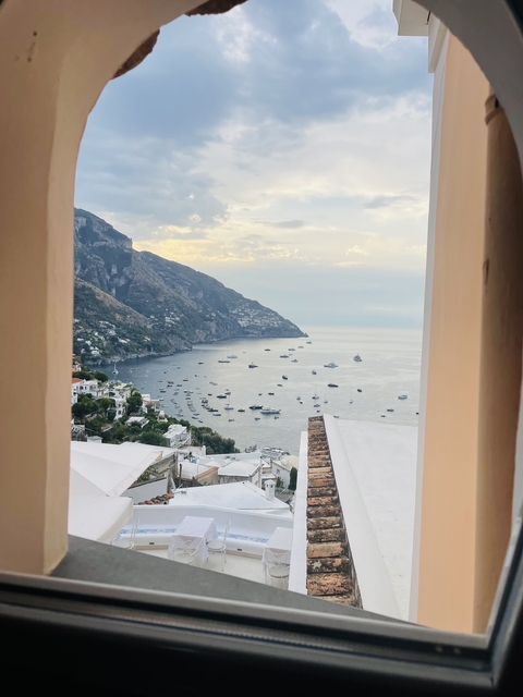 View from a window of a coastal village and boats on the ocean.