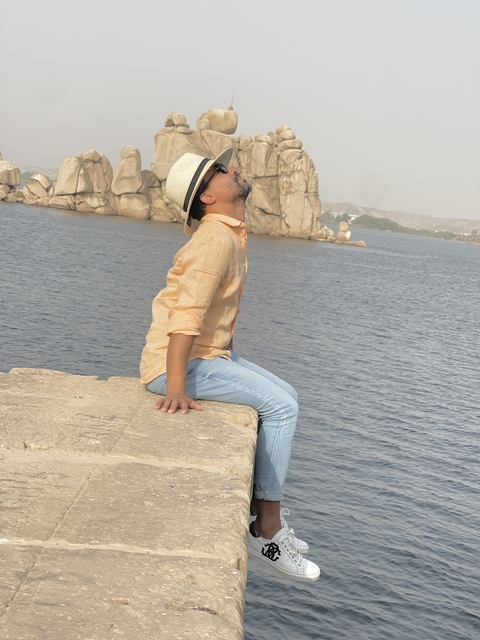 Person sitting by a river with rock formations.