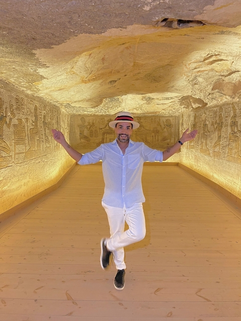 Person posing inside an ancient chamber with carvings.