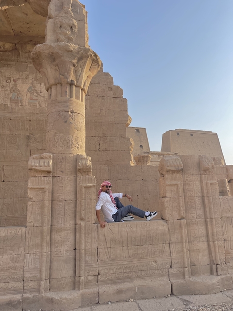 Person relaxing at a temple with hieroglyphs.
