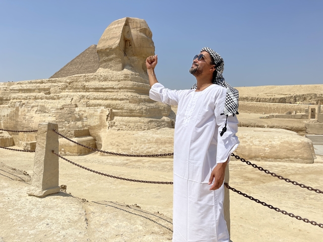 Person posing with the Sphinx and Giza pyramids.