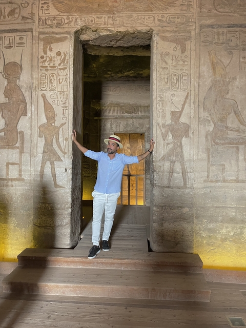 Person inside ancient stone structure with wall carvings.