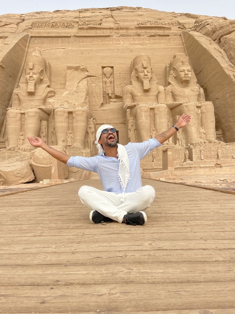 Person celebrating in front of Abu Simbel temple statues.
