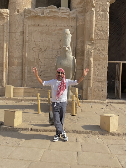 Person standing next to a large statue at a temple.