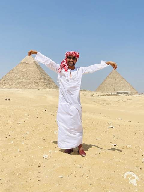 Person jumping with pyramids in the background.