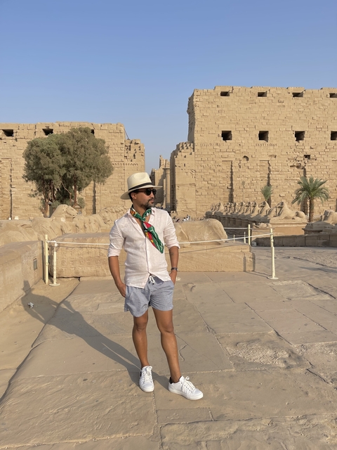 Person in sunglasses and hat near temple ruins.