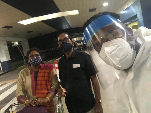 Travelers wearing face masks and a shielded driver pose for a late-night arrival photo at an airport terminal.