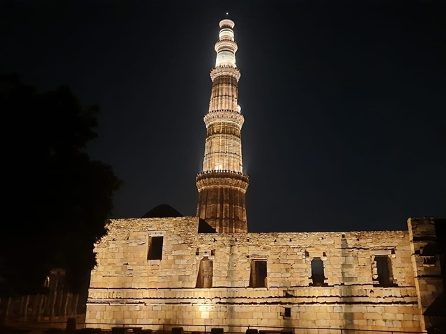 The Qutub Minar tower illuminated at night in New Delhi.