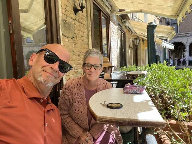 Couple seated at an outdoor cafe with a charming backdrop.