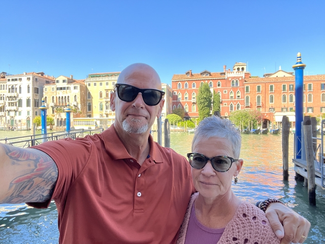 Couple posing with canal and historic buildings in Venice.