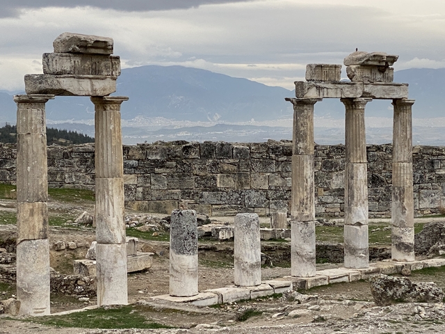 Ancient stone columns with mountains in the background.