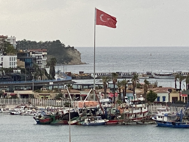 A harbor view with boats and a Turkish flag in the foreground.