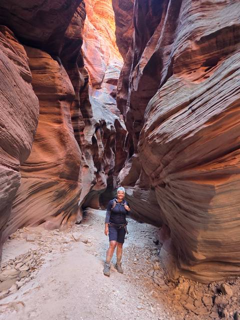 Person standing inside a narrow orange rock canyon
