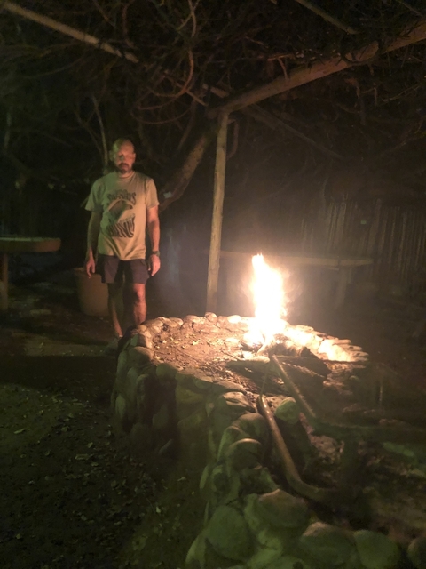 Person standing near a campfire at night.