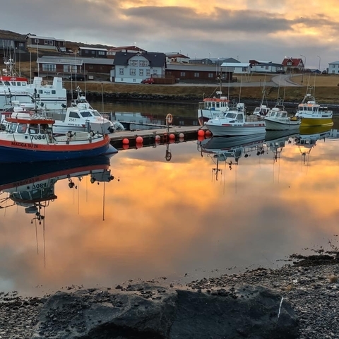 Reflection of boats in a harbor with a sunset sky