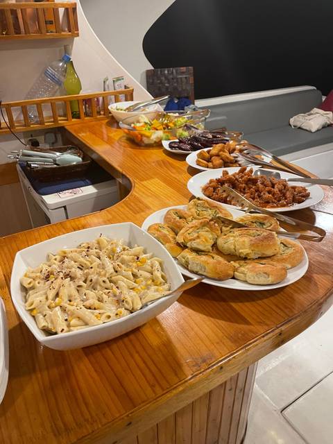 Various dishes including pastries and pasta on a buffet table.