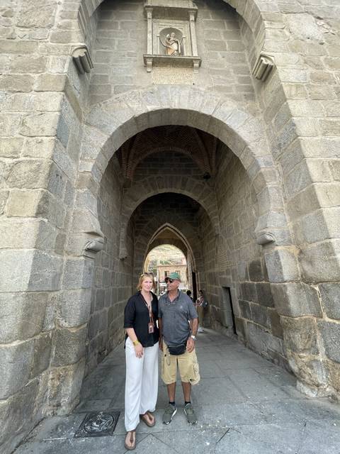 Two people standing under a stone archway.