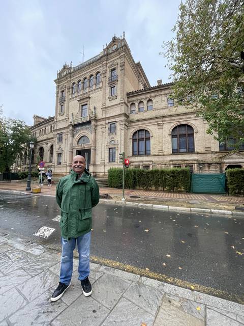 Person posing beside a historic building.